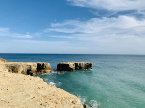 brown rock formation on sea under blue sky during daytime