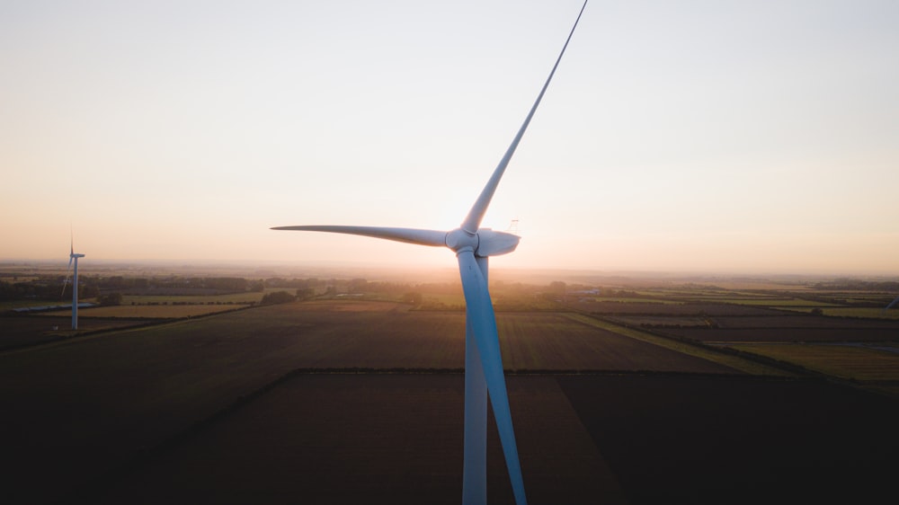 white wind turbine on brown field during daytime