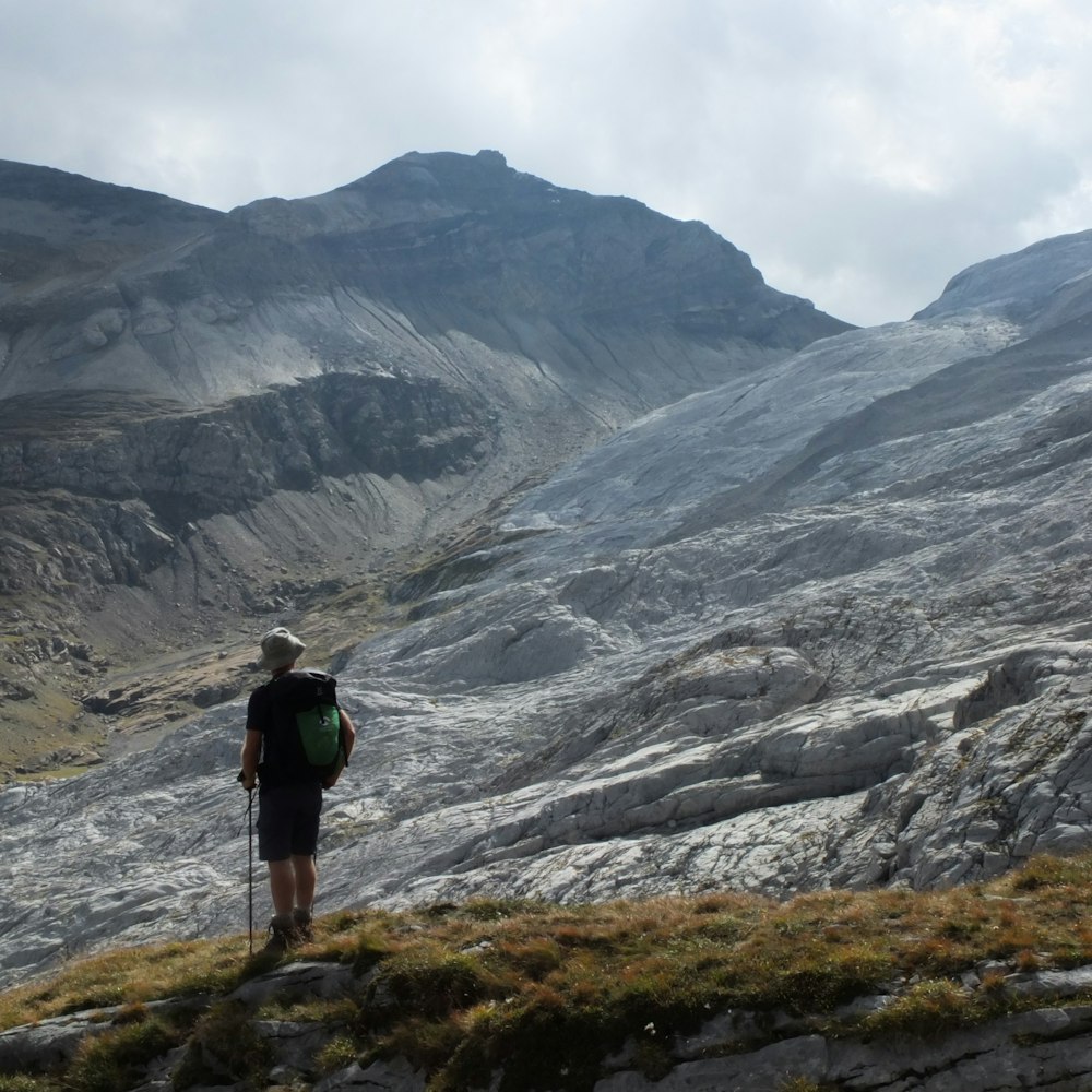 person in black jacket and black pants standing on rocky mountain during daytime