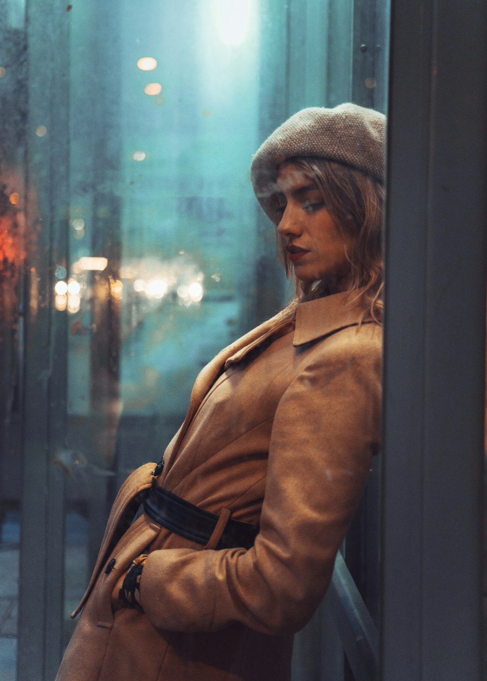 woman in brown coat standing beside glass window