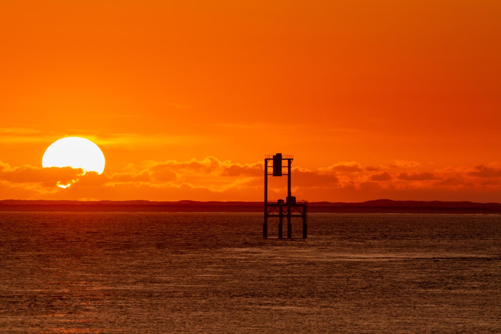 silhouette of a person standing on a wooden post during sunset