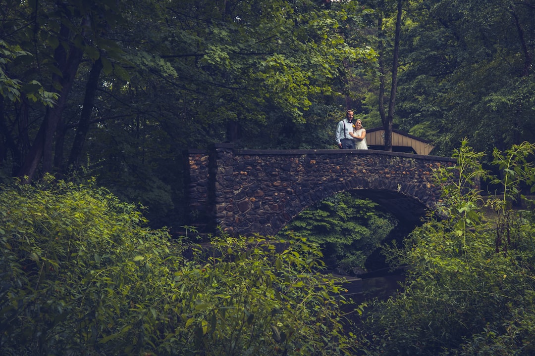 woman in white shirt standing on brown concrete bridge