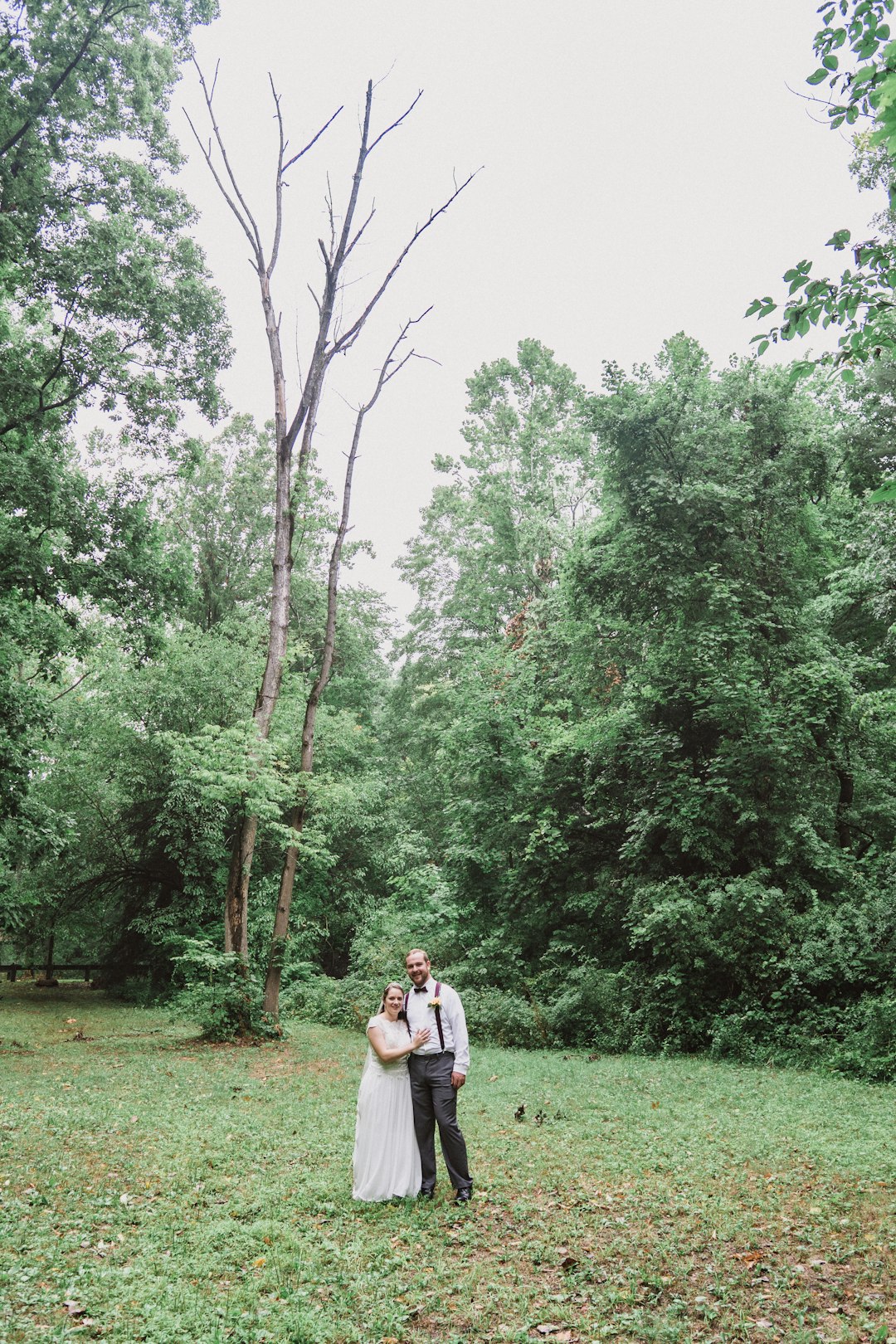 couple walking on green grass field surrounded by green trees during daytime