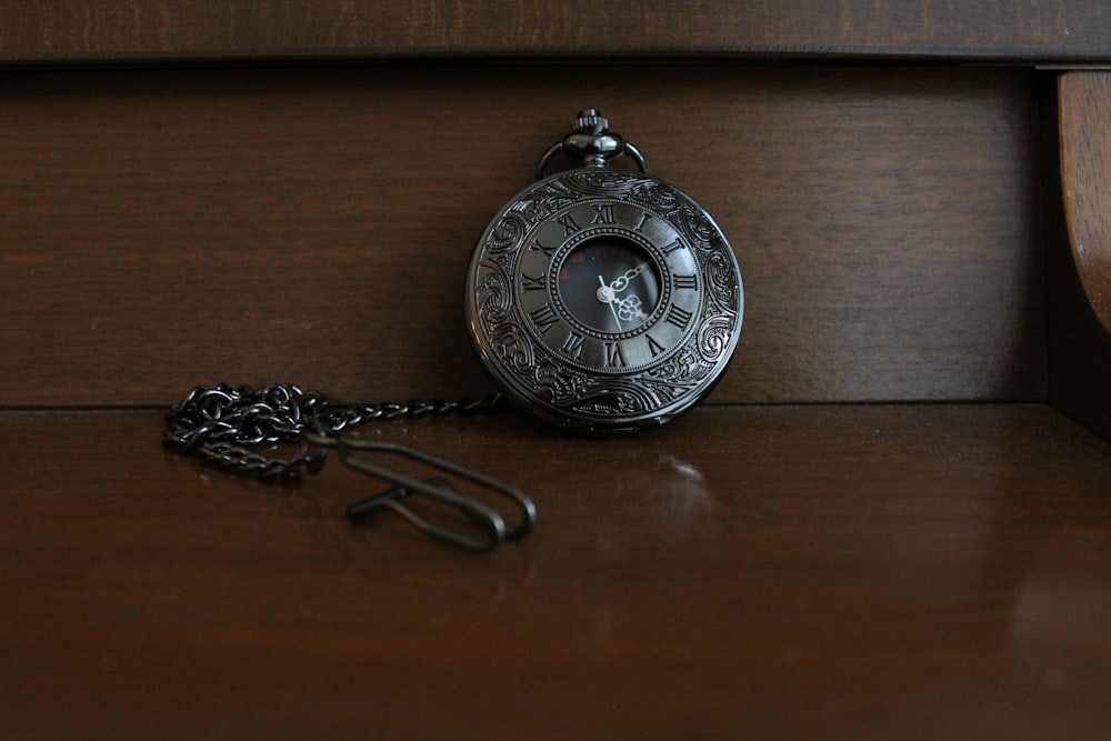 silver round pendant on brown wooden table