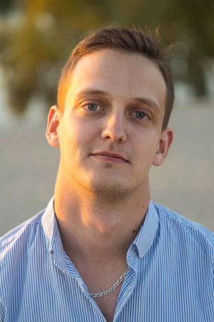 A casual look featuring a man in a short-sleeve shirt paired with jeans, smiling under natural light.