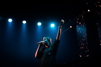 man in black t-shirt singing on stage