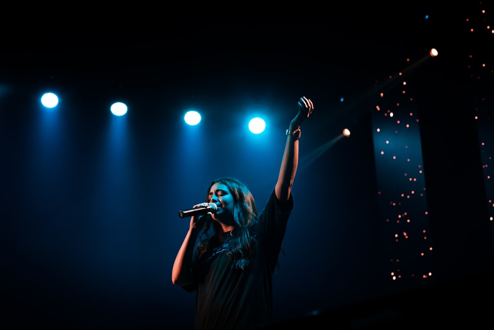 man in black t-shirt singing on stage