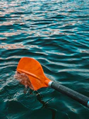 Close-up of a colorful paddle resting on a wooden dock by the water