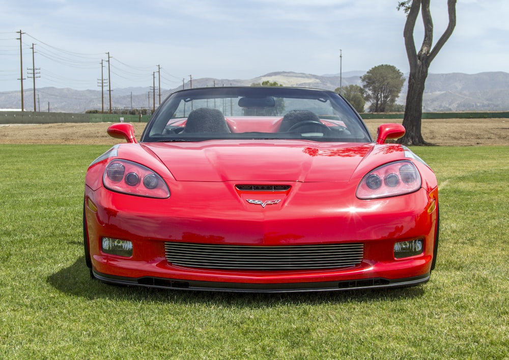 red chevrolet camaro on green grass field during daytime