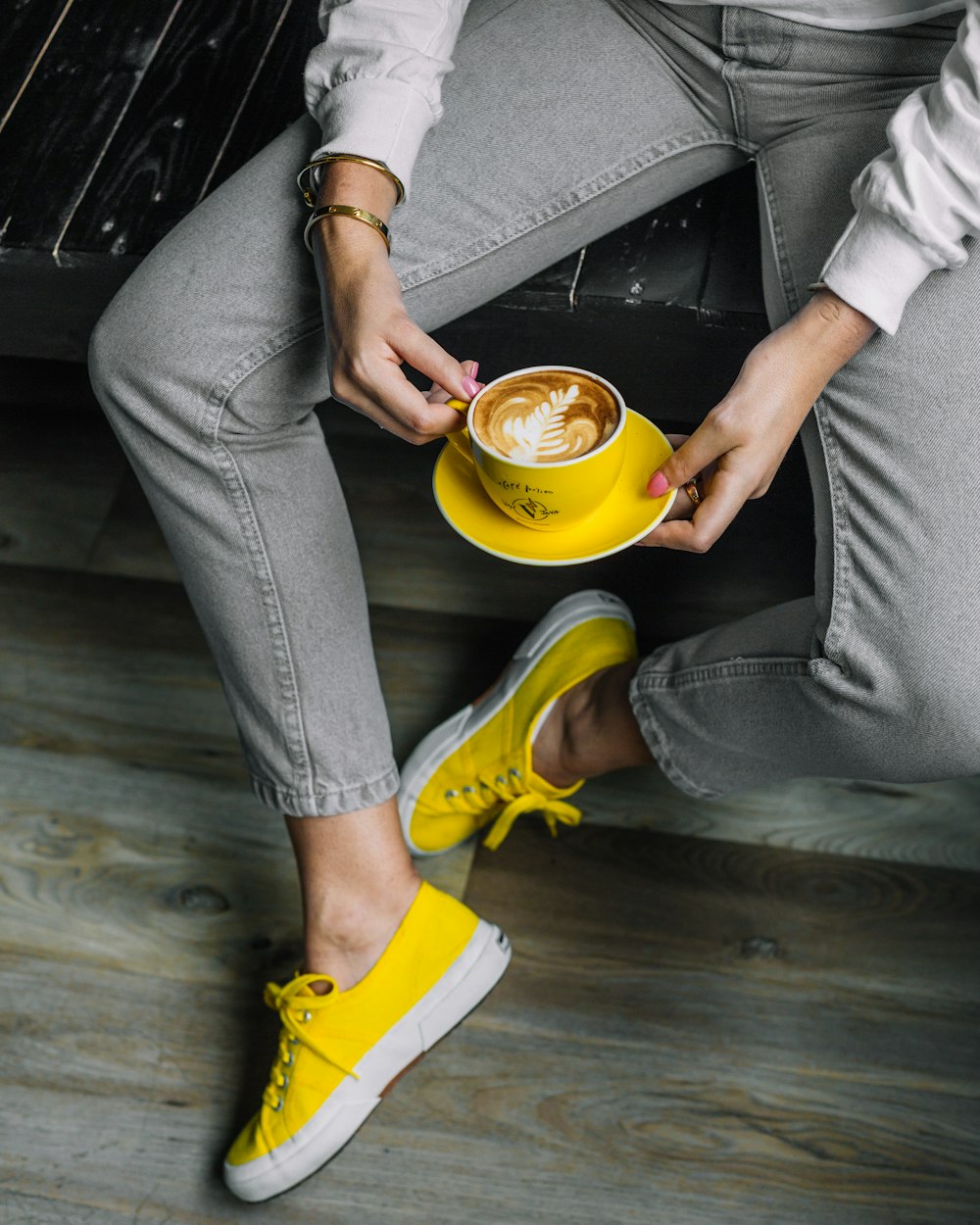 person in gray pants and yellow shoes holding yellow ceramic mug