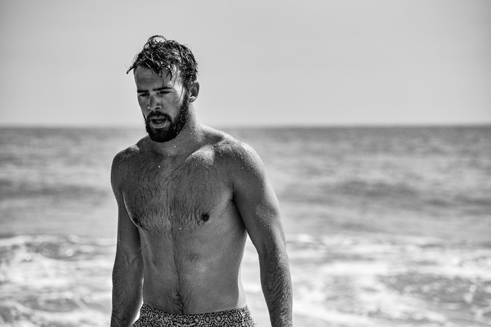 topless man in black shorts standing on beach