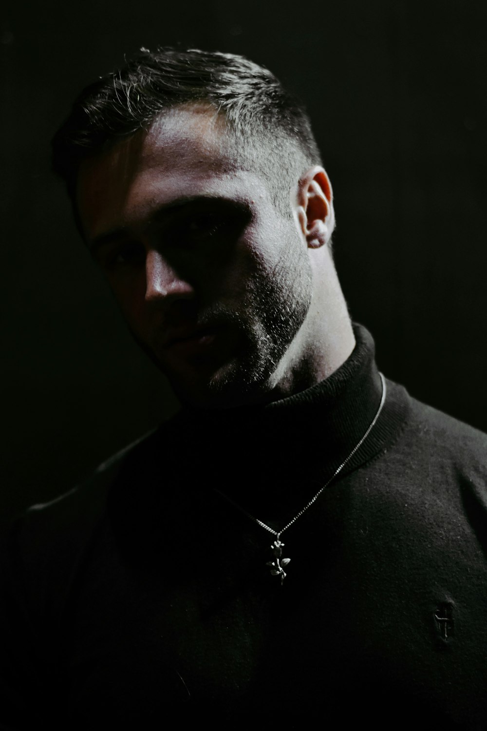 man in black hoodie wearing silver cross pendant necklace
