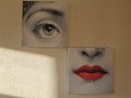 Two separate canvases depict fragments of a face. The upper canvas shows a detailed illustration of an eye, while the lower canvas displays a nose and a pair of red lips. The artworks have a dotted screen effect, reminiscent of pop art. Light from a window casts a shadow on the textured wall beside them.