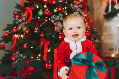 Smiling children opening Christmas gifts in a festive community gathering.