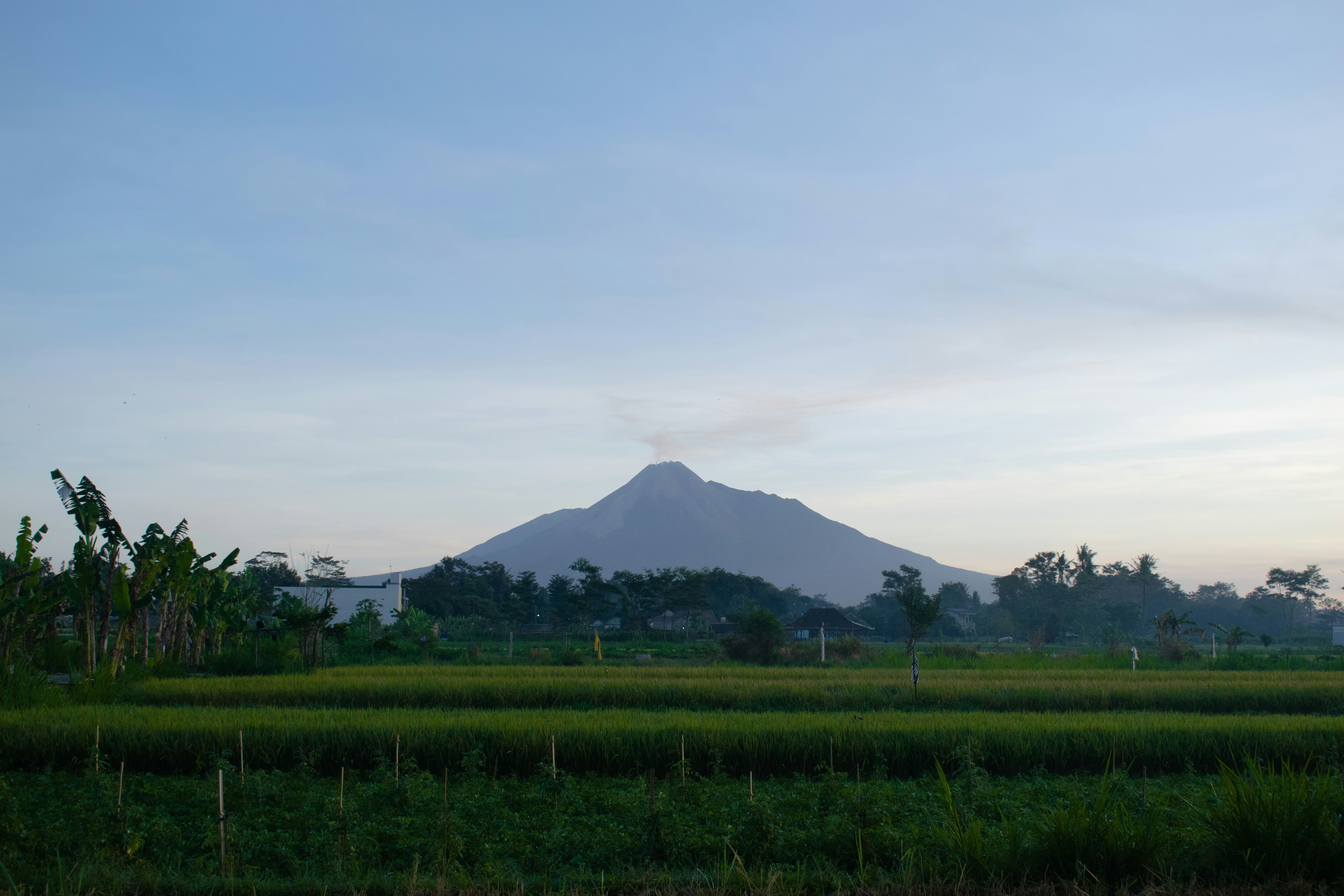 green grass field near mountain under white clouds during daytime