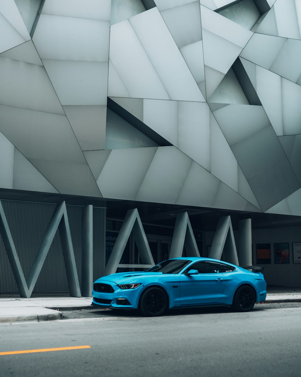 blue coupe parked beside gray building
