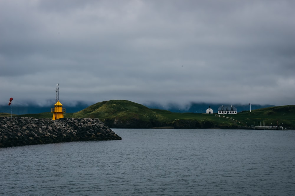 yellow and black tower on green grass field near body of water