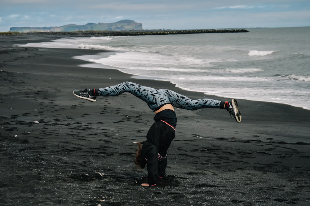 man in black pants and white and black jacket lying on beach shore during daytime