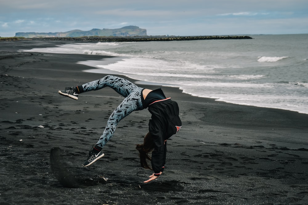 man in black jacket and black pants walking on beach shore during daytime