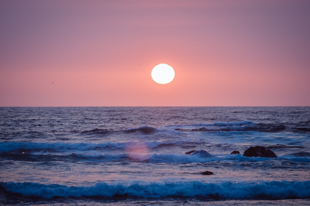 ocean waves crashing on shore during sunset