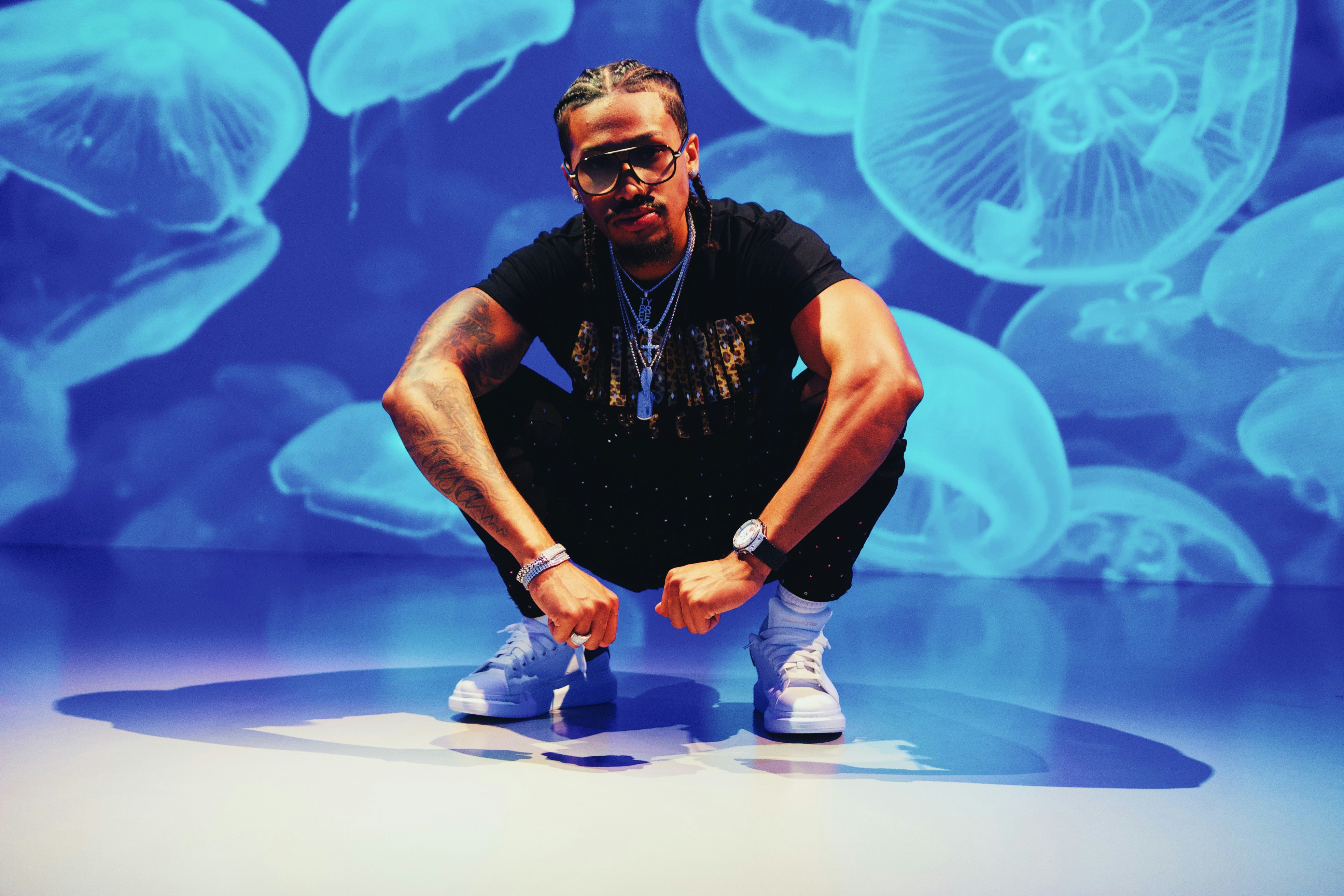 Hombre con camiseta negra de cuello redondo y jeans de mezclilla azul sentado sobre una mesa blanca