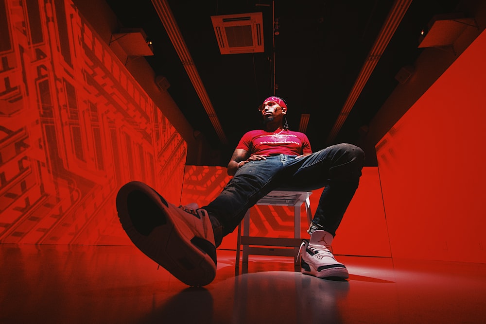 man in red t-shirt and black pants sitting on floor