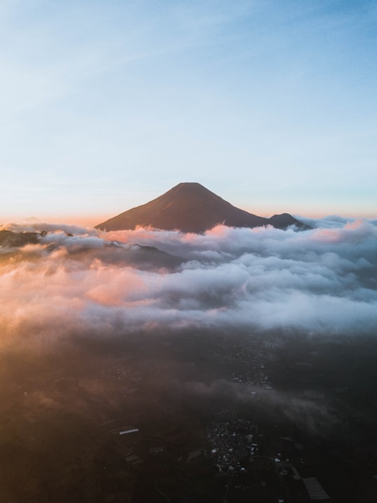 white clouds over mountain during daytime in Dieng Indonesia