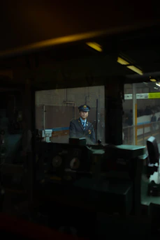 A vigilant security officer in uniform monitoring a sleek CCTV control room with multiple screens displaying city and corporate building views at night.