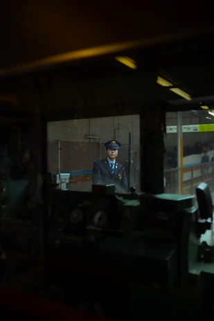 Security guard attentively monitoring an industrial site at dusk with company logo visible on uniform.