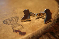 A set of polished cufflinks resting on a velvet pouch, catching soft light.