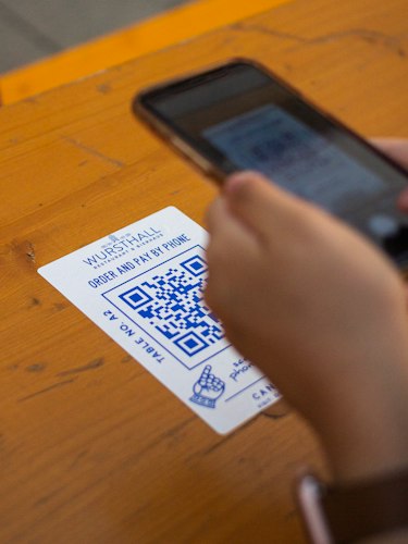 Close-up of a hand holding a smartphone displaying a QR code at a ticket gate