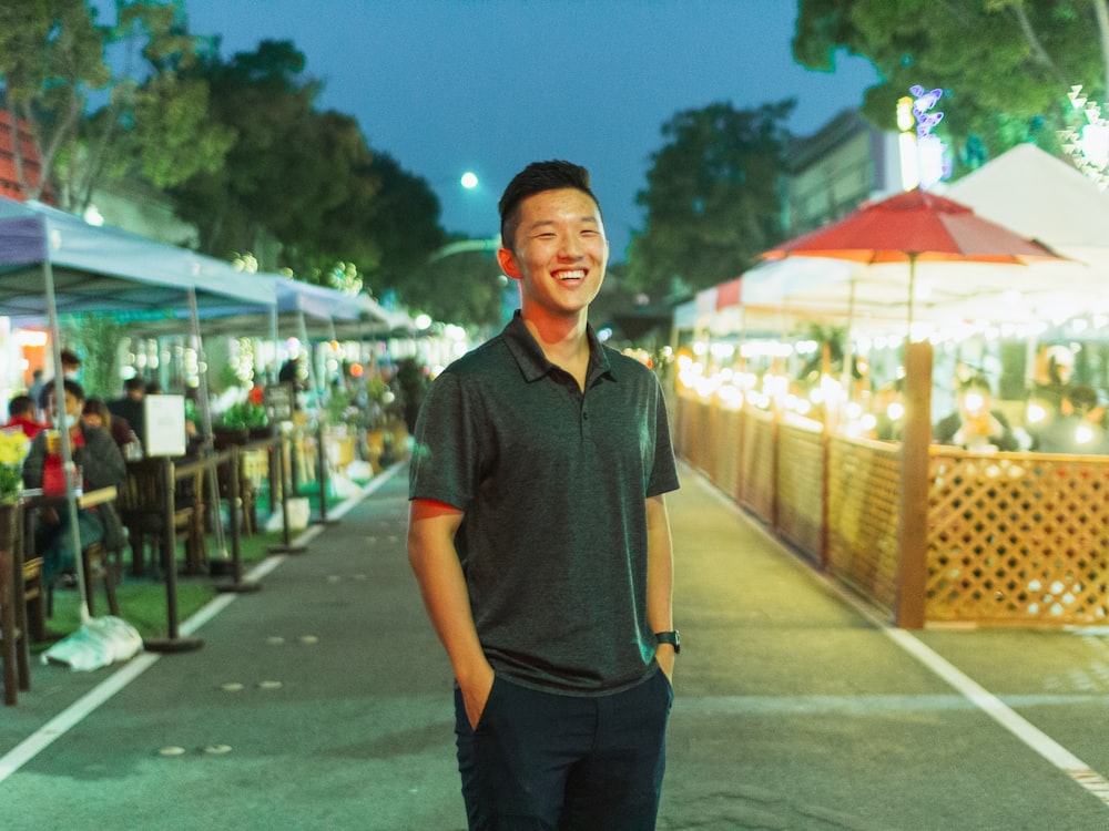 man in black polo shirt standing on road during daytime