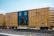 A freight train boxcar with a yellow exterior is parked on a set of railroad tracks. The side of the boxcar has the letters 'TTX' and the phrase 'RAILCAR POOLING EXPERTS' prominently displayed. The boxcar has instructions printed on the doors, and various mechanical details like wheels and coupling mechanisms are visible.