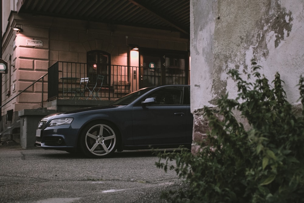 black car parked beside white concrete building