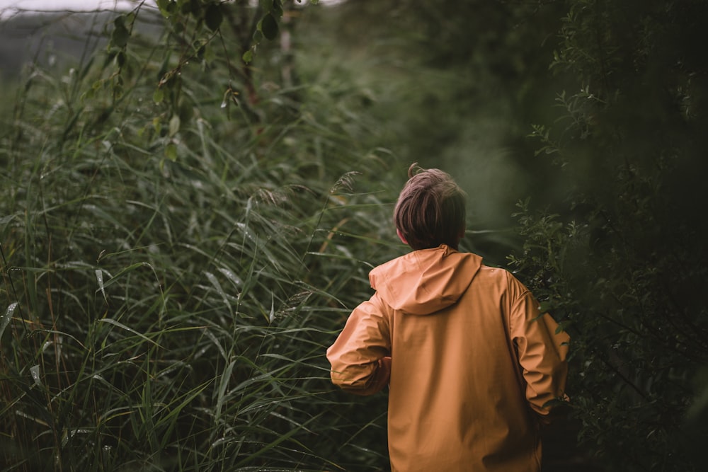 person in brown hoodie standing in the woods during daytime