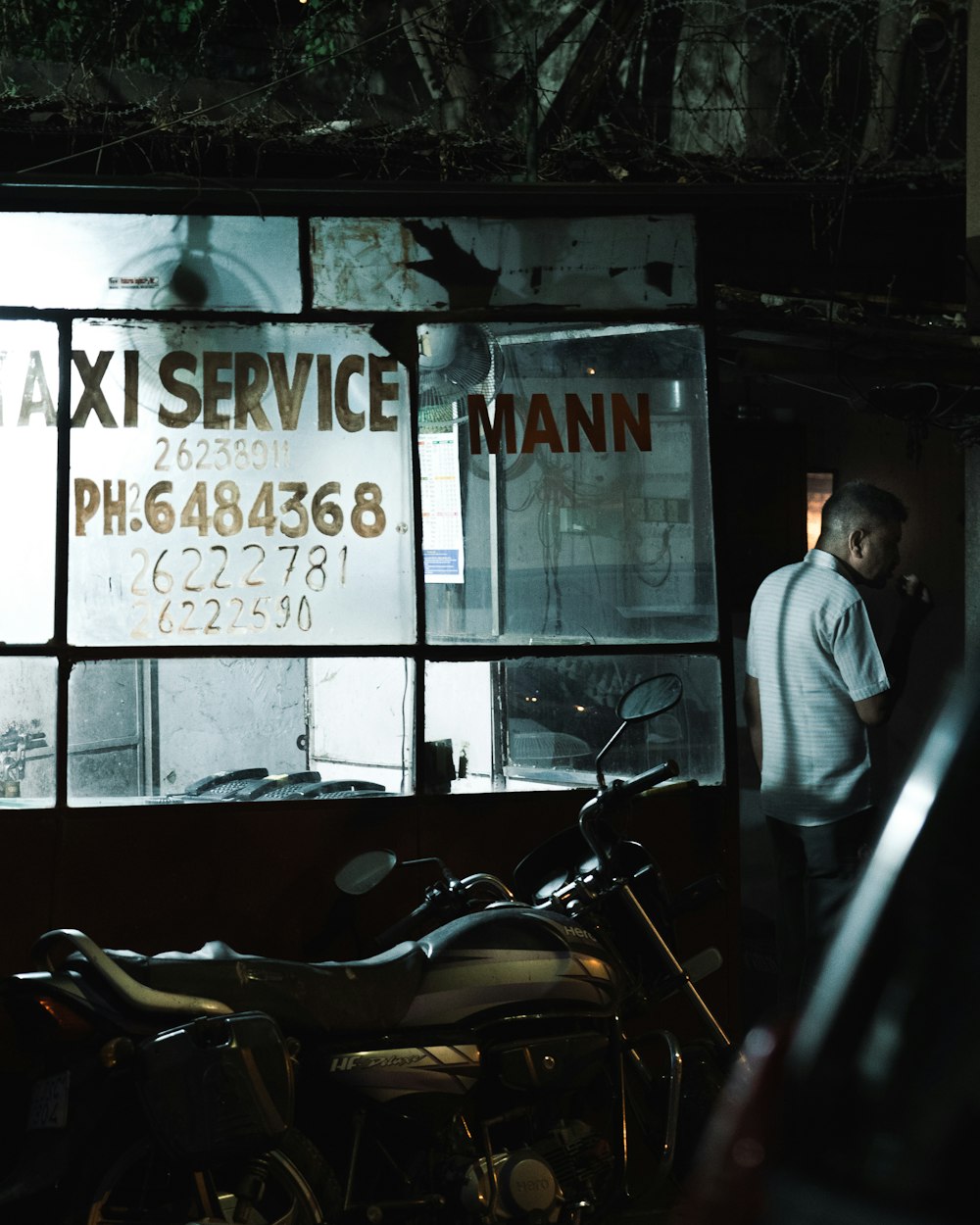 man in white dress shirt standing beside black motorcycle