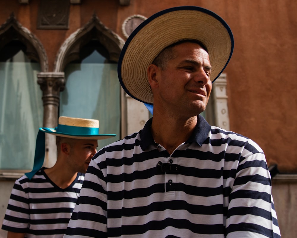 man in black and white striped polo shirt wearing brown hat