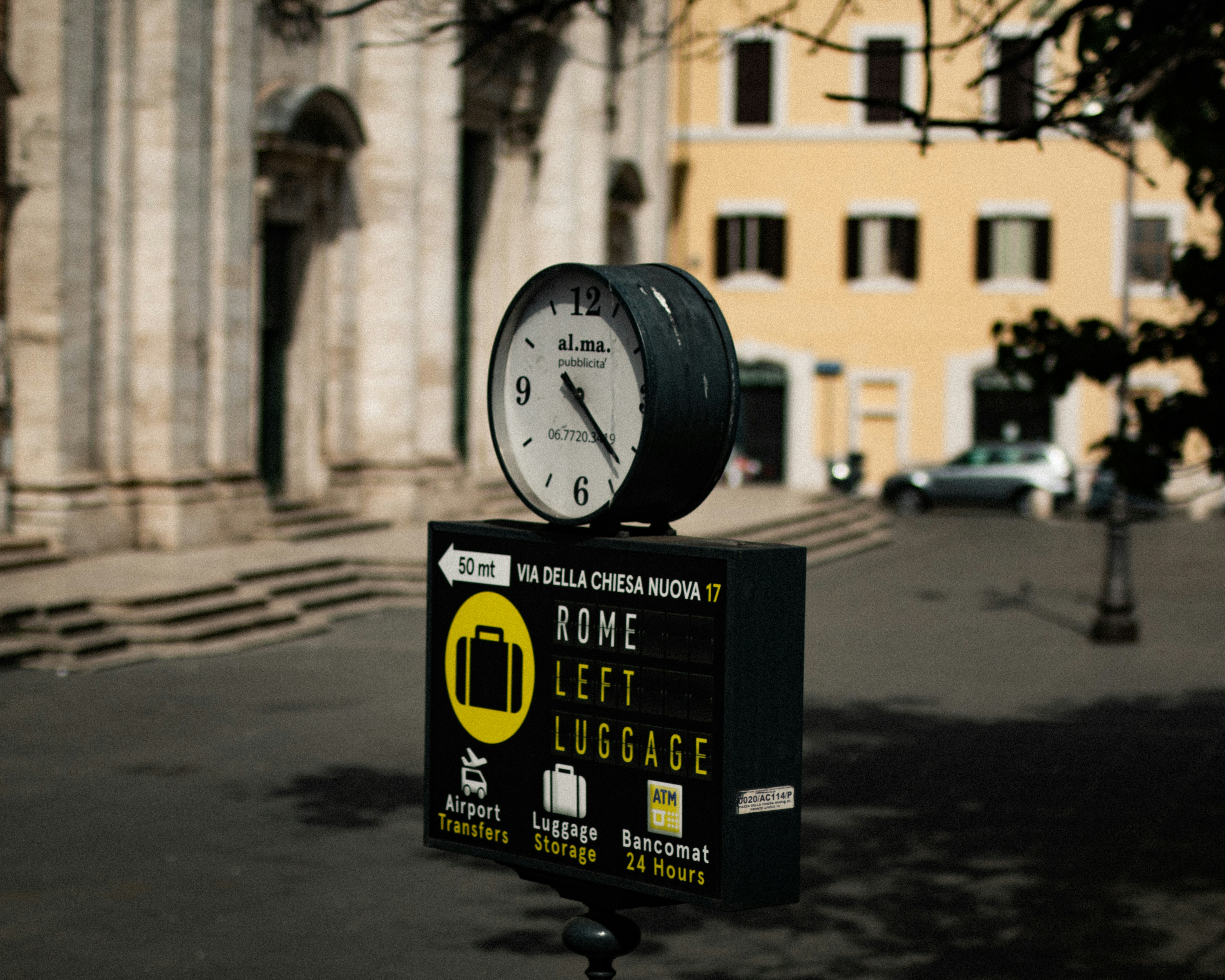 a clock sitting on top of a sign in front of a building