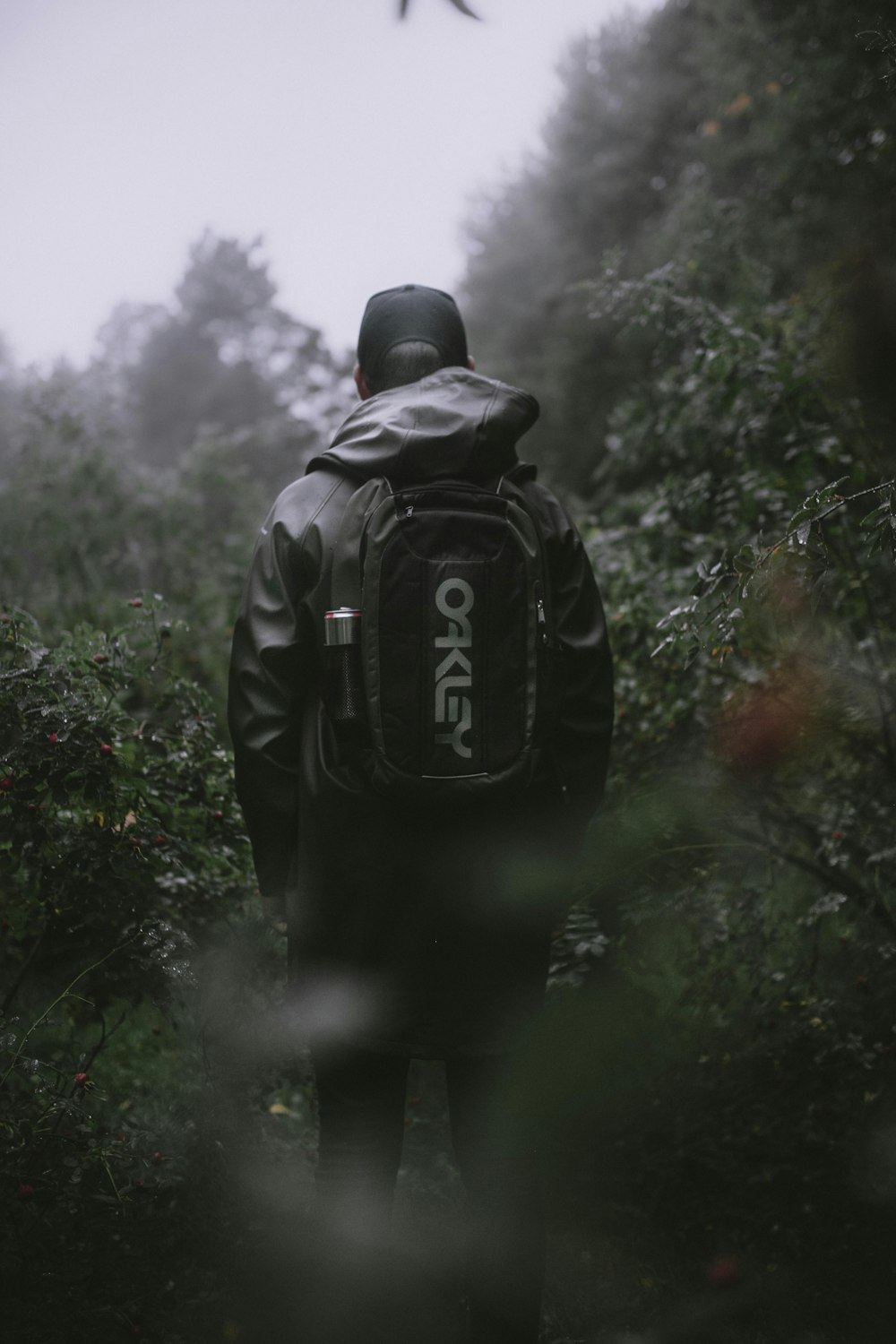 man in black jacket and black backpack standing on green grass field during daytime