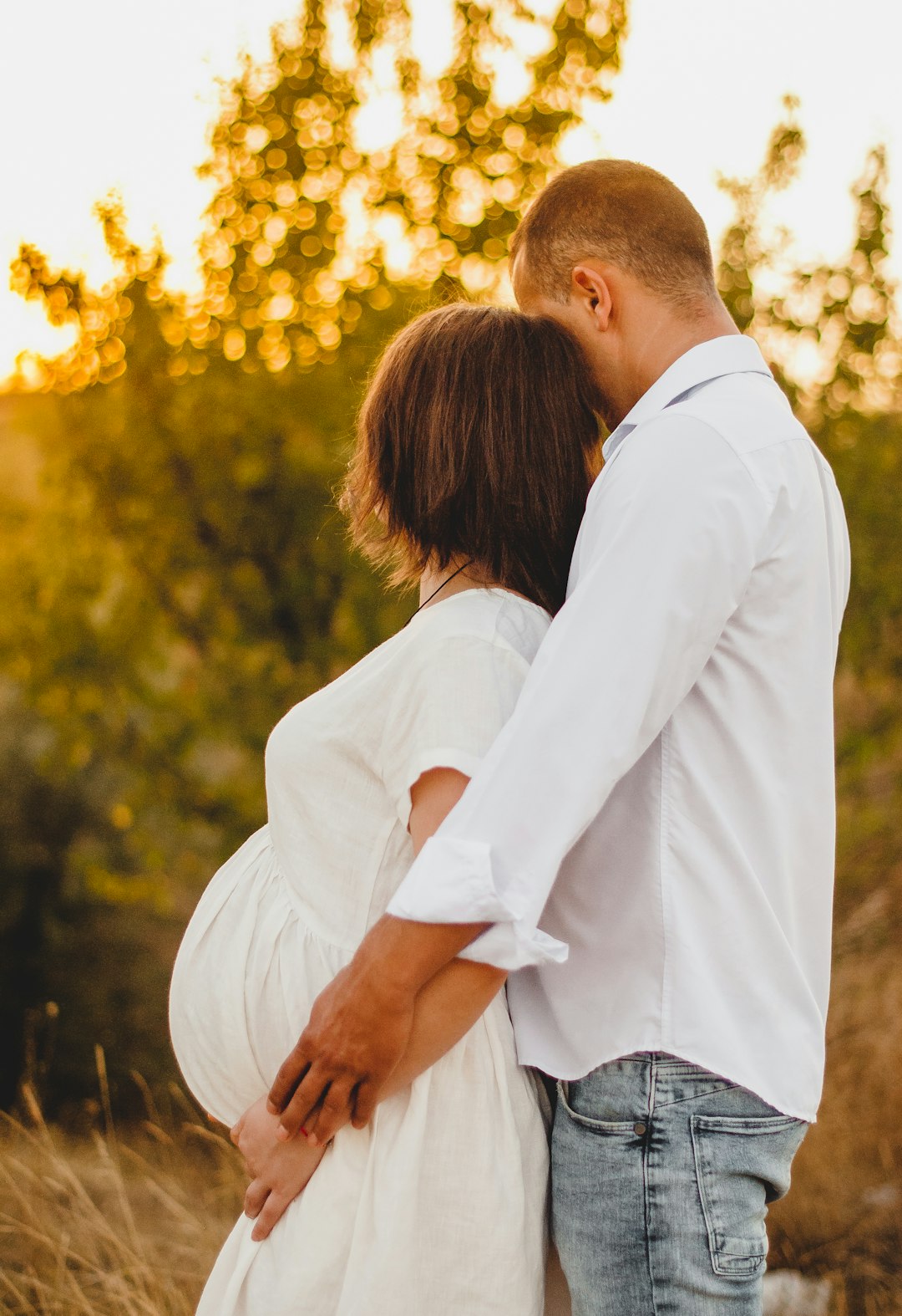 man in white dress shirt hugging woman in blue denim jacket