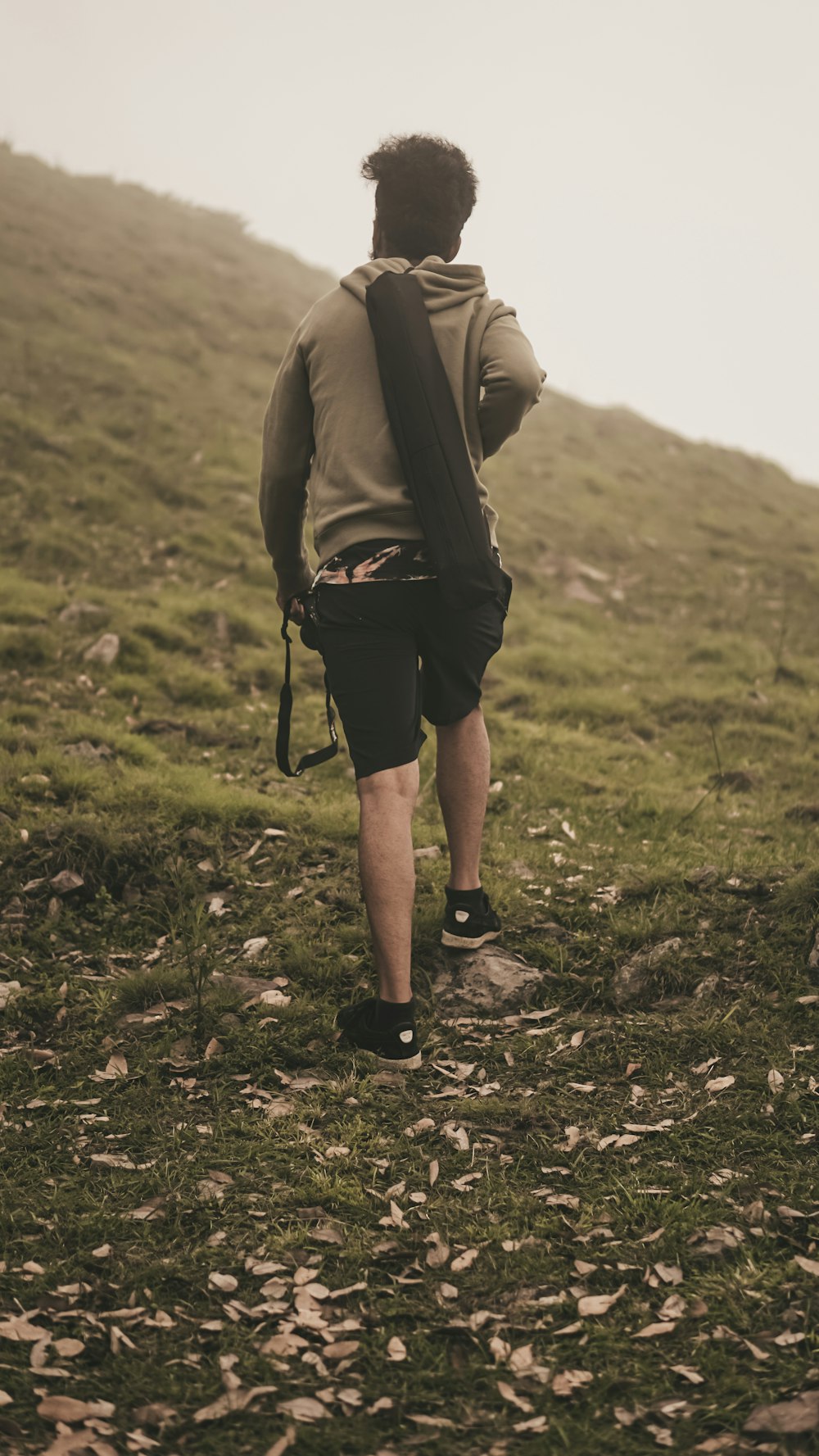 person in black shorts walking on green grass field during daytime