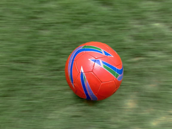 A dynamic shot of a soccer ball mid-air, branded with Vigora, on a green field.