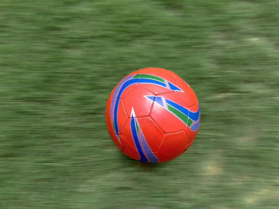 A dynamic SVG animation of a soccer ball spinning over a lush green pitch background.
