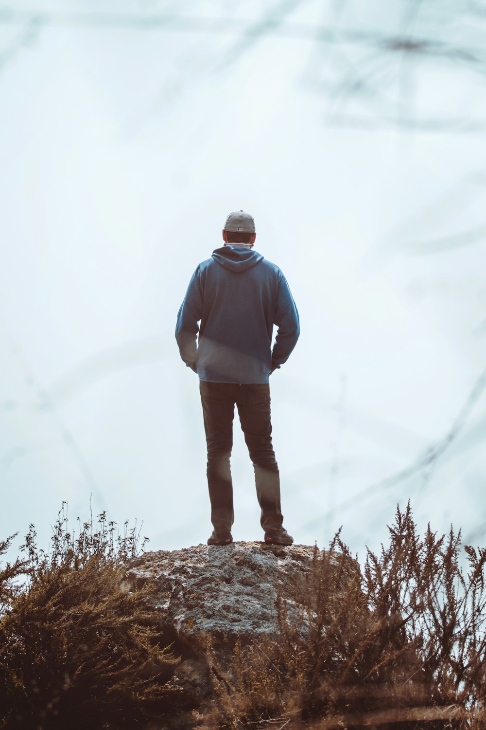 man in blue hoodie standing on brown grass during daytime