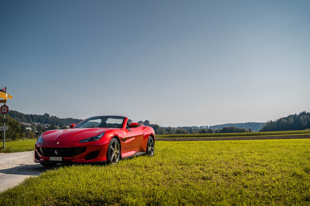 red ferrari 458 italia on green grass field under blue sky during daytime