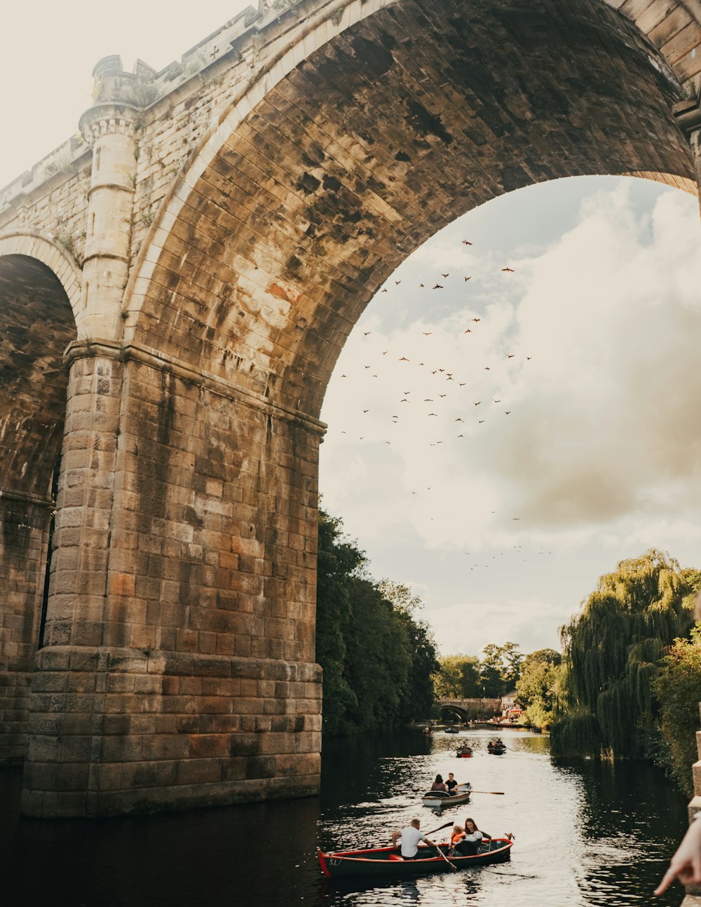 brown concrete bridge over river under white clouds during daytime