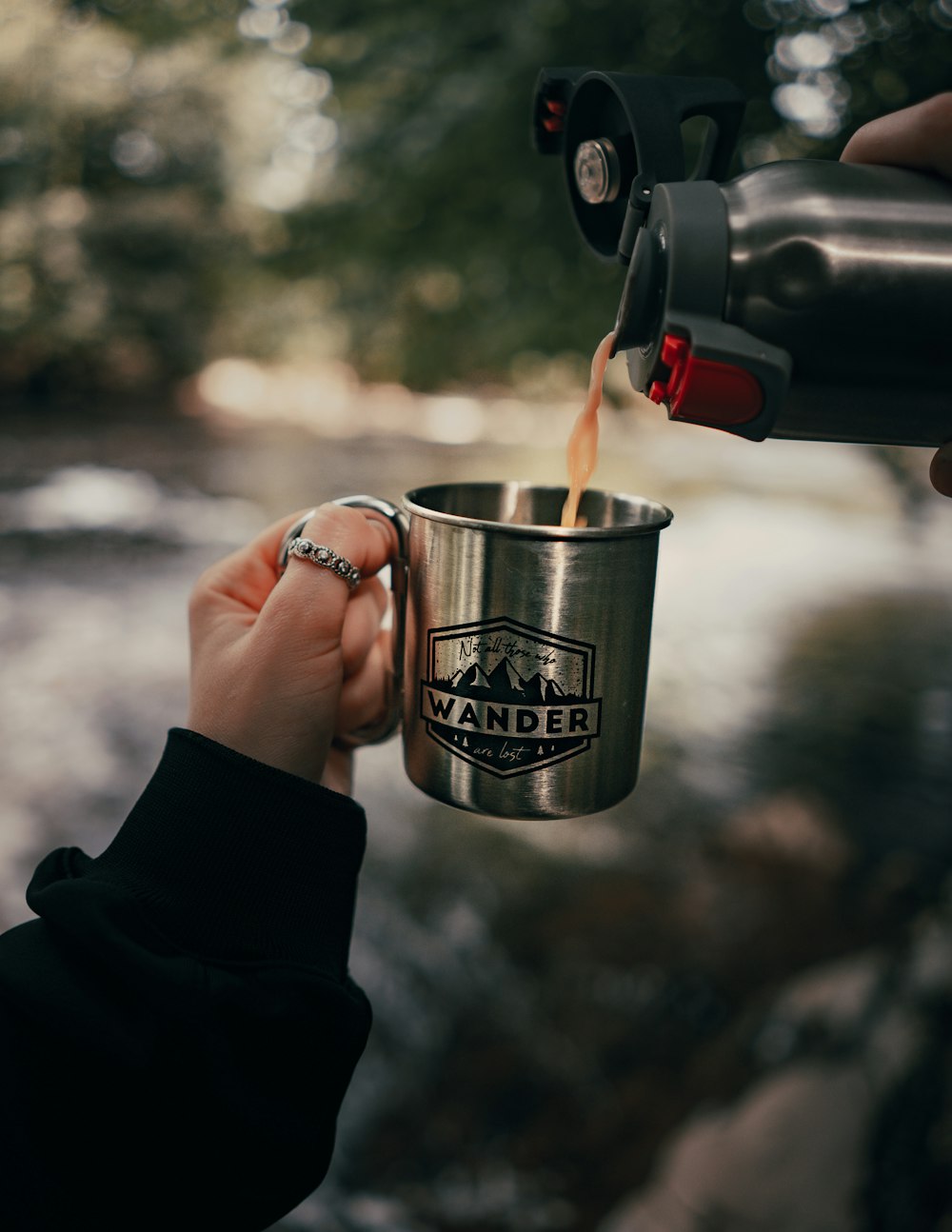 person holding silver and black mug