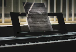 Sheet music spread out on a piano with soft black and orange ambient lighting.