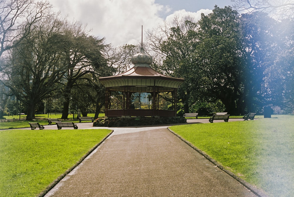 Brauner und weißer Pavillon, tagsüber umgeben von grünen Bäumen unter blauem Himmel