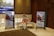 A conference hall with a display featuring two promotional standees showcasing a family in traditional attire, highlighting a product related to agriculture. There is a statue of a man seated with a child on his shoulders and a patterned table. The lighting is warm and the decor includes elegant paneling and chandeliers.